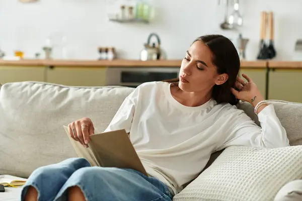 Relaxing at home, the beautiful woman absorbs the pages of a book, surrounded by comfort. — Stock Photo
