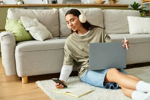 Woman lounges comfortably at home, engaged in activities with her laptop and smartphone. — Stock Photo