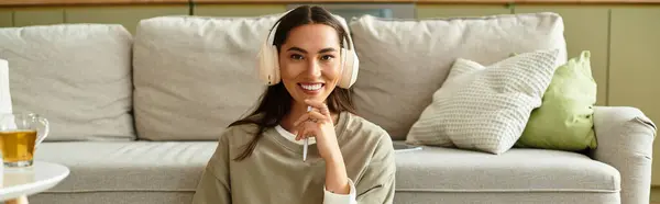 Young woman relaxes in her cozy living room, enjoying music while seated comfortably. — Stock Photo