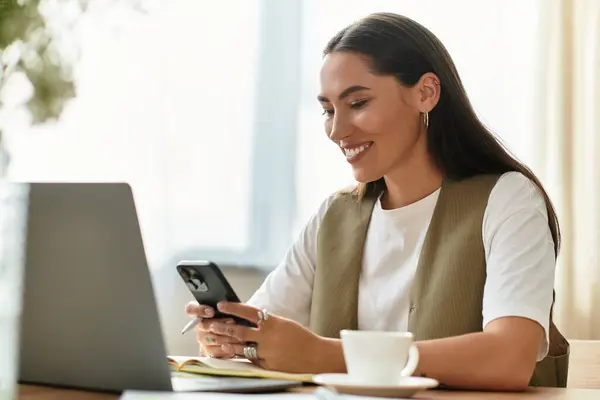 Una joven se relaja en casa, felizmente comprometida con su smartphone. - foto de stock