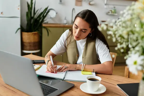 A young woman sits at a wooden table, sipping coffee and writing in her planner. — Stock Photo