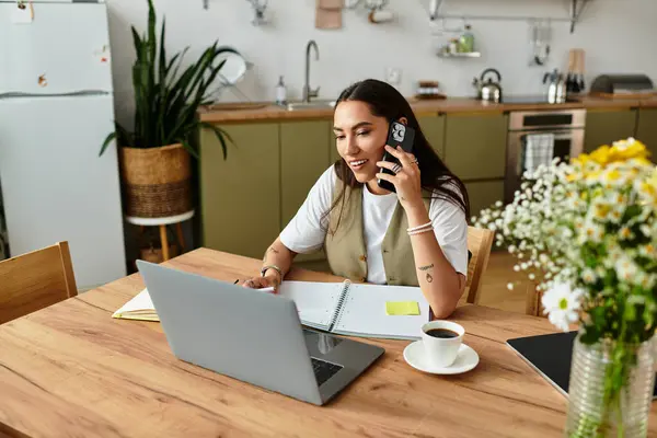 A young woman relaxes at home, chatting on the phone and using her laptop. — Stock Photo