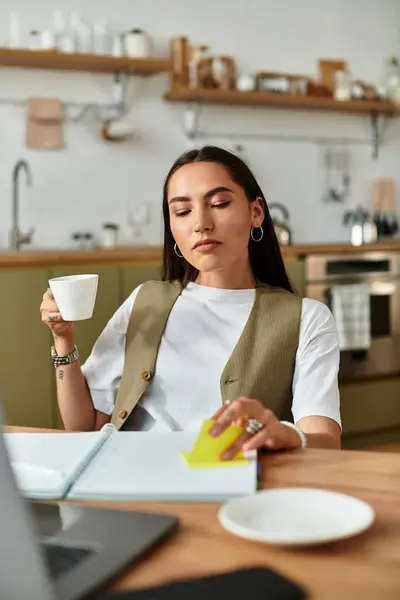 A serene young woman sips coffee while thoughtfully engaged in her writing task at home. — Stock Photo