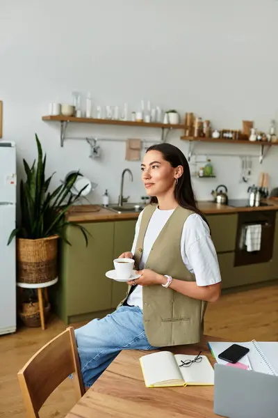 La mujer se sienta cómodamente en casa, saboreando el café y disfrutando de un momento tranquilo de reflexión. - foto de stock