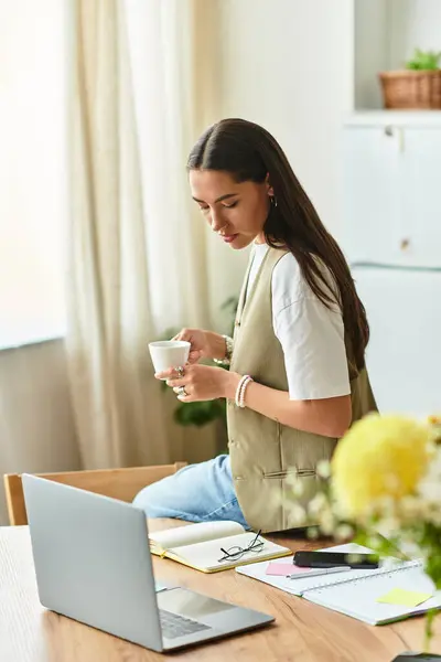 Young woman in a comfy outfit relaxes at home while sipping tea and working on her laptop — Stock Photo