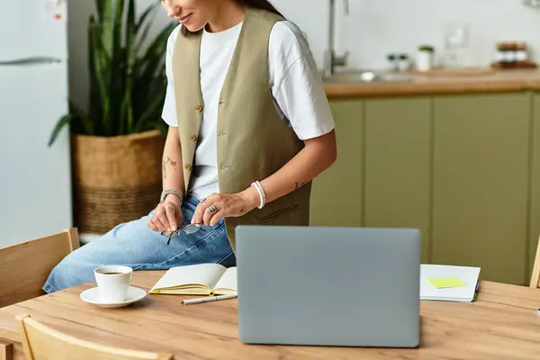 Una giovane donna si rilassa nella sua confortevole casa, concentrandosi sul suo computer portatile mentre sorseggia caffè. — Foto stock