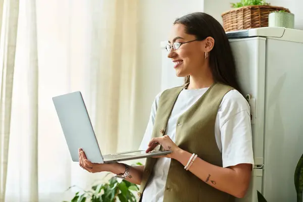 Bright sunlight fills the room as a young woman gracefully interacts with her laptop, laughing. — Stock Photo