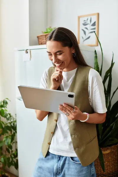 A young, pretty woman smiles as she interacts with her tablet in her cozy home environment. — Stock Photo