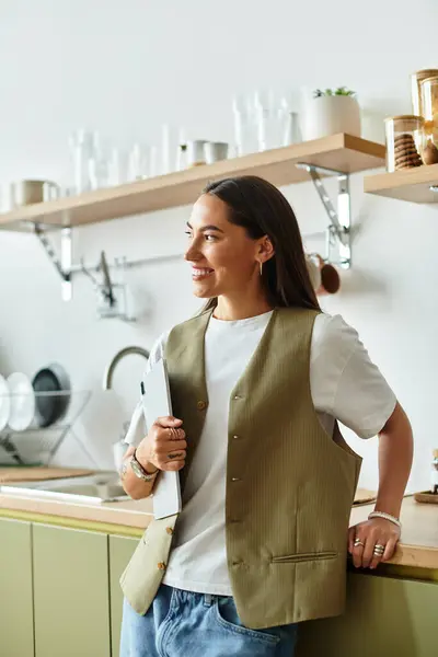 Young woman with a warm smile stands comfortably in a well decorated kitchen, embracing home life. — стоковое фото