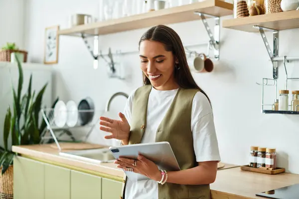 A beautiful young woman engages with her tablet at home, surrounded by a cozy kitchen ambiance. — Stock Photo