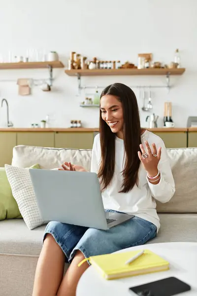 A young woman shares smiles and laughter from her comfy couch during a virtual chat at home. — Stock Photo