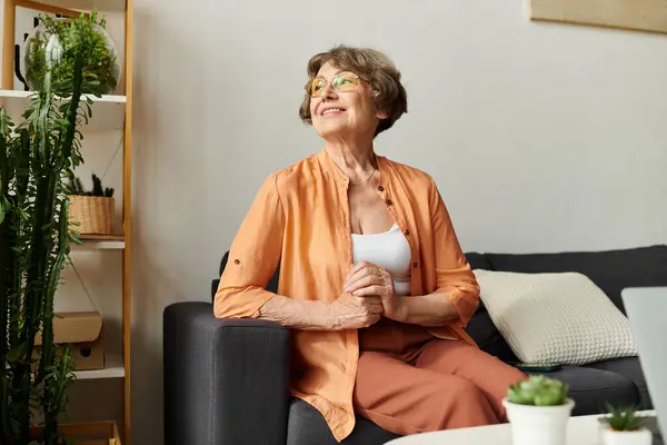 Smiling senior woman in cozy attire sits at home, radiating warmth and happiness. — Stock Photo