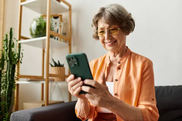 A relaxed woman smiles while using her smartphone in a cozy home. — Stock Photo