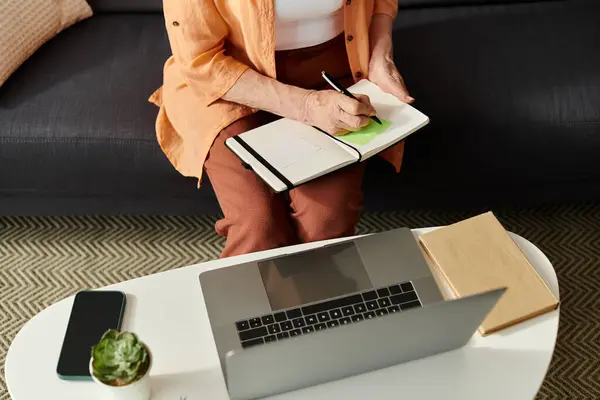 A mature woman in comfy clothes journals at home on a sunny afternoon. — Stock Photo
