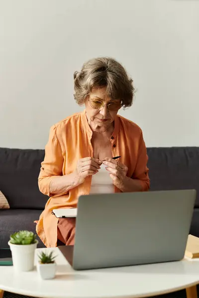 Mature woman in comfy clothes focuses on her laptop at home in a relaxed afternoon. — Stock Photo