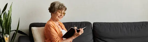 In a cozy room, an older woman writes in her journal, savoring a peaceful afternoon. — Stock Photo