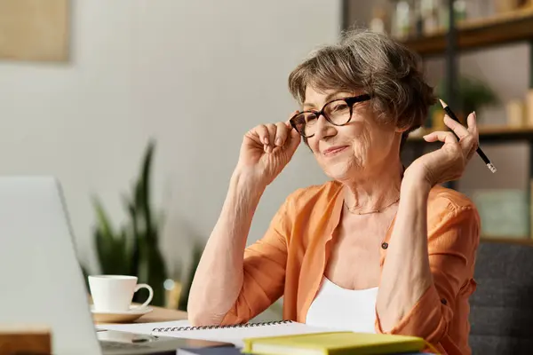 Mature woman in comfortable attire smiles while working on a creative project in her cozy home. — Stock Photo