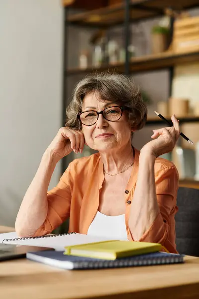 A warm smiling lady in cozy attire writes in a notebook in a serene setting. — Stock Photo