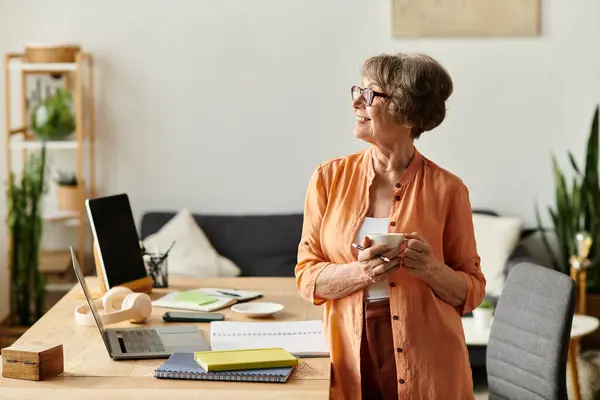 Senior woman in cozy attire stands in her home, sipping a warm drink and enjoying the moment. — Stock Photo