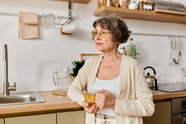 Senior woman relaxes at home, sipping a warm drink and enjoying her cozy surroundings. — Stock Photo