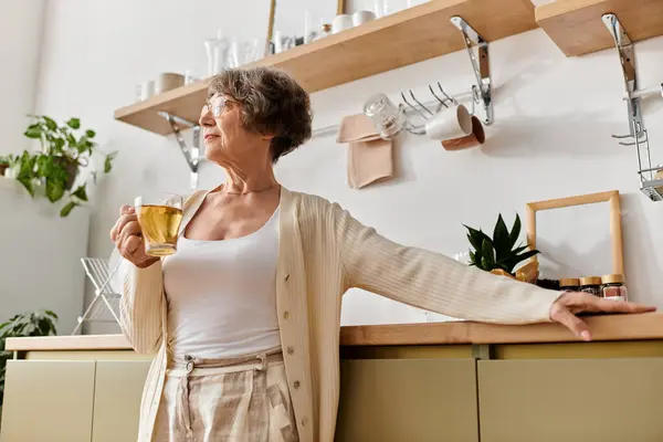 In einer ruhigen häuslichen Umgebung genießt eine reife Frau ein warmes Getränk, während sie sich gemütlich fühlt. — Stockfoto