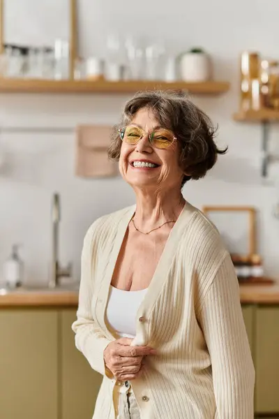 A senior woman in cozy attire smiles warmly while enjoying a peaceful moment at home. — Stock Photo
