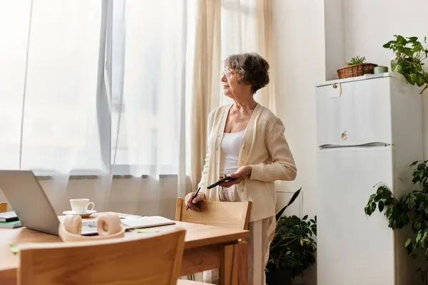 A senior woman relaxes by the window, enjoying the warm daylight in her cozy space. — Stock Photo