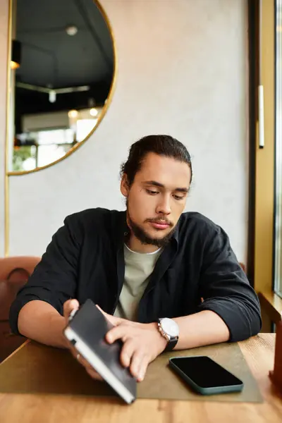 Joven con barba trabaja en un elegante café, inmerso en la creatividad. — Stock Photo