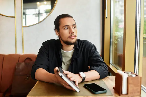 Young man with a beard sitting at a serene cafe during summer days. — Stock Photo