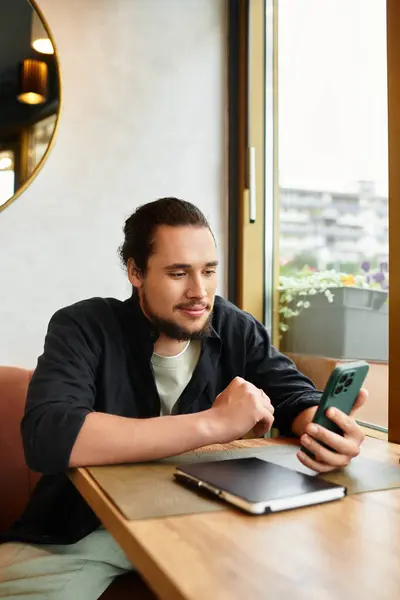 A young man with a beard focuses on his smartphone in a cafe. — Stock Photo