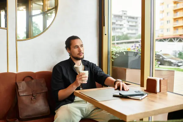 Young man with a beard sips his drink at a cafe, enjoying a summer day — Stock Photo