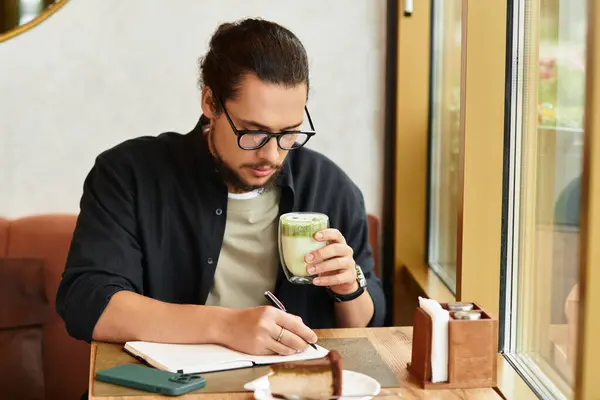 Freelancer sips matcha and writes notes in a cozy cafe, enjoying summer vibes and delicious cake. — Stock Photo