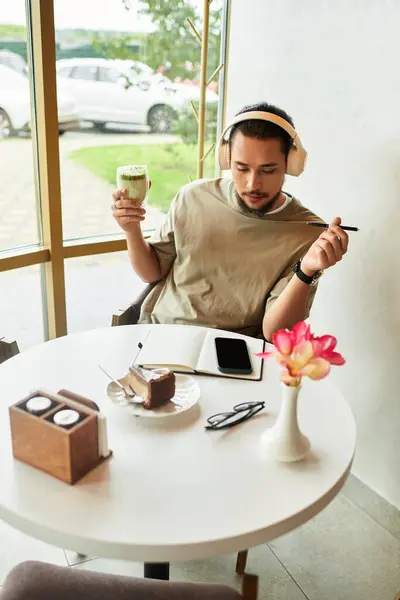 Remote worker relaxes in a cafe, sipping matcha and jotting notes while enjoying summer vibes. — Stock Photo