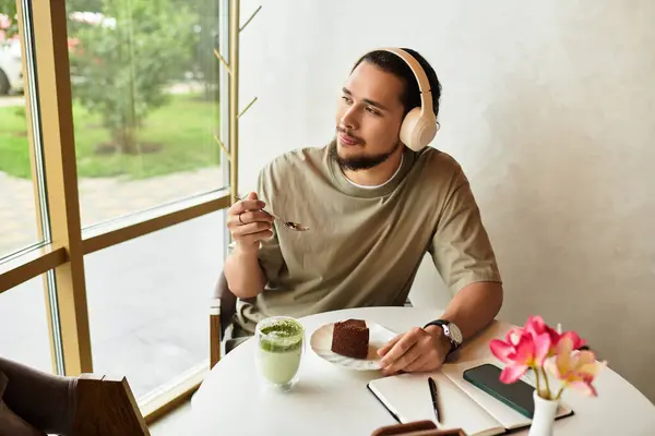 A young man with a beard takes a moment to savor dessert and drink in a cafe. — Stock Photo