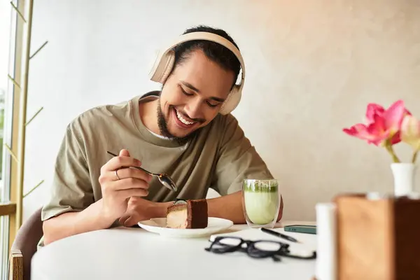 A young man enjoys cake and matcha in a summer cafe. — Stock Photo