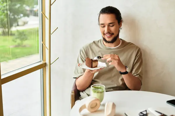 Man savoring a delicious cake slice and matcha drink in a cozy cafe. — Stock Photo