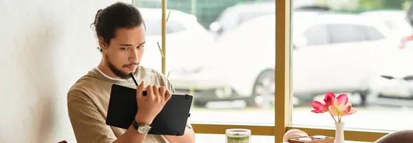 Un joven barbudo tomando notas en un acogedor café, pancarta — Stock Photo