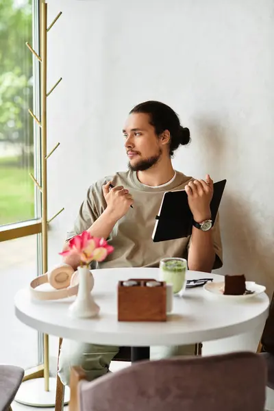 Young man with a beard taking notes in cafe — Stock Photo