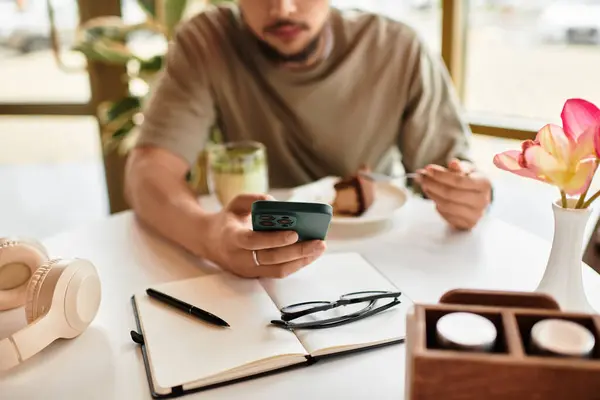 Young man with a beard engages in remote work while savoring matcha and cake. — Stock Photo