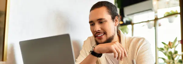 A young man with a beard focuses on his laptop, immersed in freelance tasks at a cafe, banner — Stock Photo