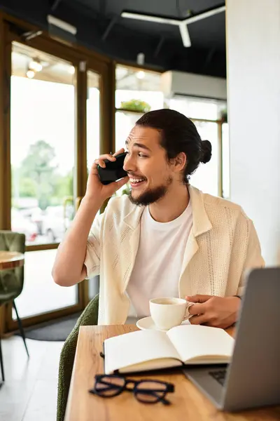 A young man with a beard is engaged in remote work while sipping coffee in a lively cafe. — Stock Photo