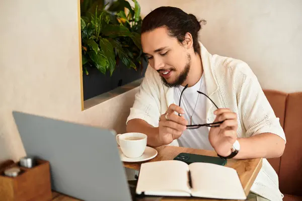 Focusing on work, a young man savors a coffee in a cozy cafe during summer. — Stock Photo