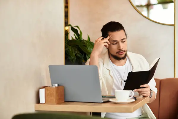 A young man with a beard deeply focused on his notes while enjoying coffee at a cafe. — Stock Photo