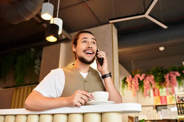 Freelancer chats on the phone while savoring coffee in a busy cafe during summer days. — Stock Photo