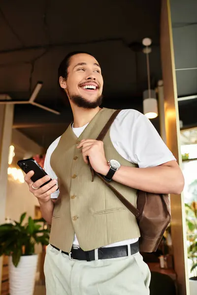 Freelancer engages with his smartphone, smiling in a vibrant cafe setting. — Stock Photo