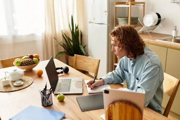 Young man engages in writing and work while surrounded by comforts of home. — Stock Photo