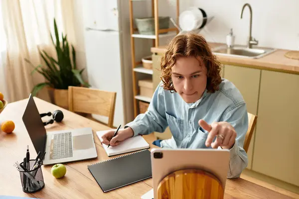 In a bright and comfortable home setting, a young man concentrates on studying while taking notes. — Stock Photo
