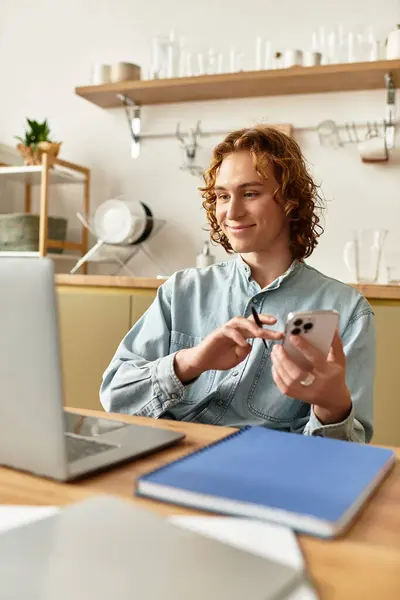 Handsome young man engages with his phone and laptop at home in a cozy environment. — Stock Photo