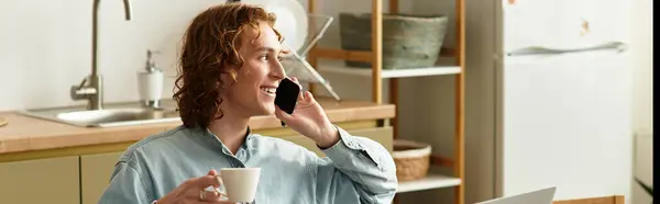 Young man smiles as he enjoys a warm beverage and engages in a friendly conversation at home. — Stock Photo