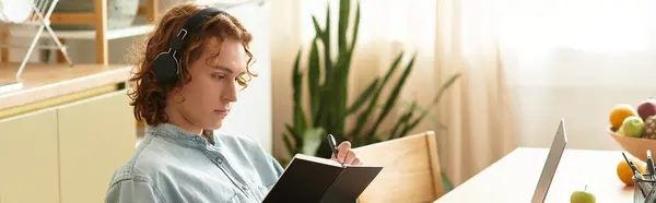 Focused on writing, a handsome young man enjoys his time at home with a notebook and laptop. — Stock Photo